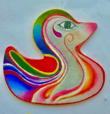 A wooden duck shape painted in flowing rainbow stripes, with one green eye.